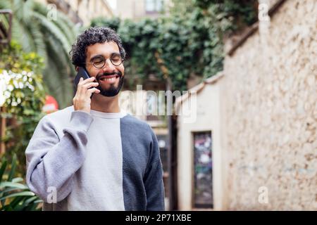giovane uomo sorridente felice parlando al telefono Foto Stock
