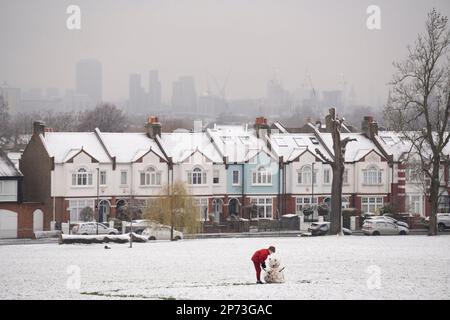 Quando la neve di marzo cade a sud di Londra, un ragazzo costruisce un piccolo pupazzo di neve di fronte alle case d'epoca, a Ruskin Park, uno spazio verde pubblico a Lambeth, il 8th marzo 2023, a Londra, Inghilterra. Foto Stock