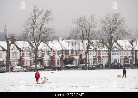 Quando la neve di marzo cade a sud di Londra, un ragazzo costruisce un piccolo pupazzo di neve di fronte alle case d'epoca, a Ruskin Park, uno spazio verde pubblico a Lambeth, il 8th marzo 2023, a Londra, Inghilterra. Foto Stock