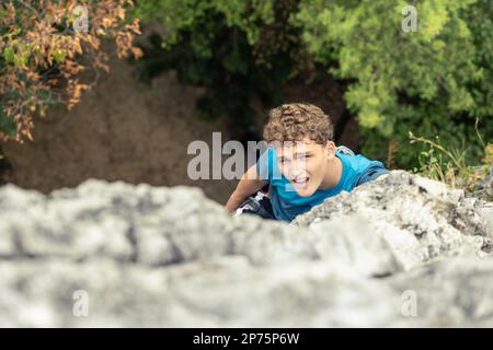 Uomo che si arrampica in montagna, guardando in avanti alla cima della montagna proprio sopra la vista. Foto Stock