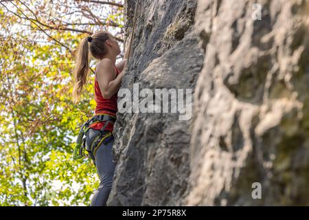 Donna che in estate si arrampica sulla parete rocciosa Foto Stock