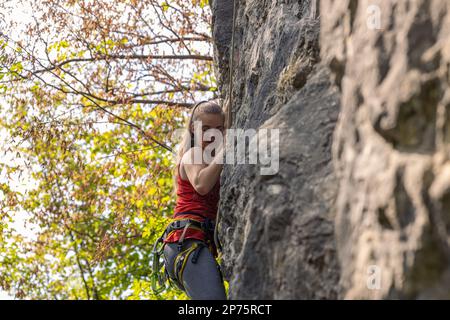 Giovane donna che si arrampica sull'alta roccia in montagna. Concetto di avventura e sport estremi Foto Stock