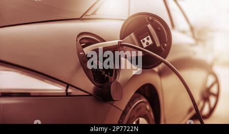 Primo piano della spina collegata all'auto elettrica. Foto Stock
