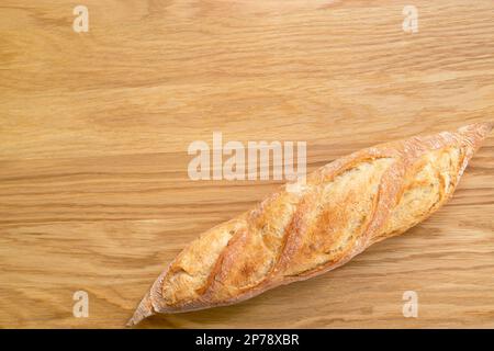 Baguette fresca su sfondo di legno, pane croccante. Vista dall'alto, copyspace. Prodotto da forno. Pagnotta lunga. Foto Stock