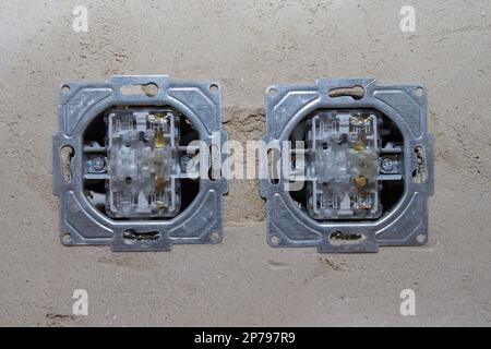 Installazione di due contatti elettrici sulla parete bianca. Foto Stock