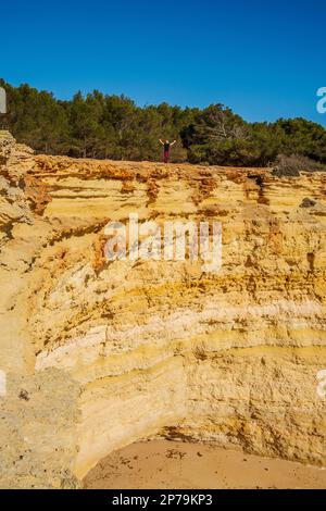 Un uomo in piedi sulla cima di scogliere giganti della spiaggia di Corredoura, Algarve, Portogallo Foto Stock