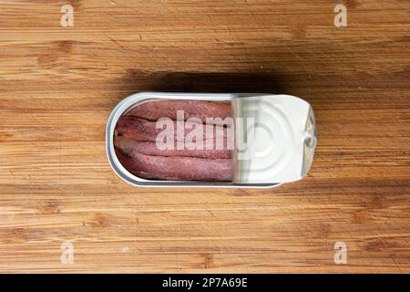 Lattina aperta di pesce Anchovy set su una tavola da cucina in legno vista dall'alto. Foto Stock