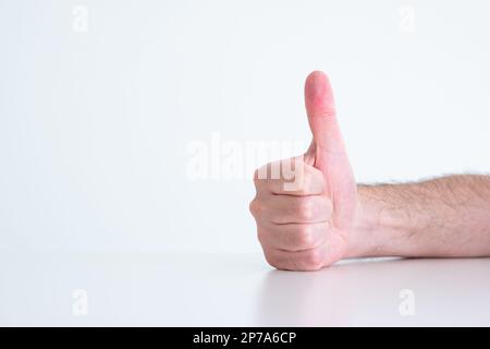 Mano maschio caucasica che fa i pollici su gesto isolato su bianco primo piano vista frontale. Foto Stock