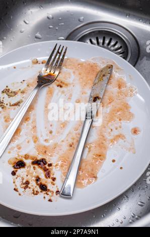 Piatti sporchi nel lavandino della cucina. Cibo salsa macchiato porcellana piatti e utensili, non persone, vista dall'alto. Foto Stock