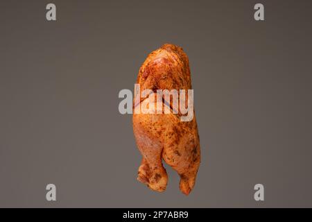 Pollo fresco intero, crudo e pronto condito. Primo piano ripresa in studio, isolata su sfondo marrone. Foto Stock