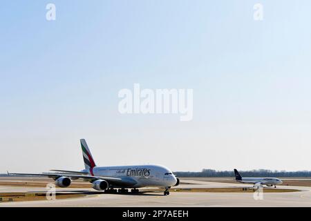 Emirates Airlines, Airbus A380-800 con Lufthansa Airbus A320 in background tassando sulla linea di taxi da Runway South al Terminal 1, aeroporto di Monaco Foto Stock