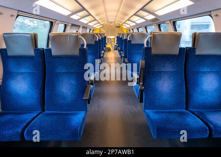 Posti a sedere blu vuoti all'interno della cabina dei treni, vista sul corridoio, nessuna persona. Foto Stock