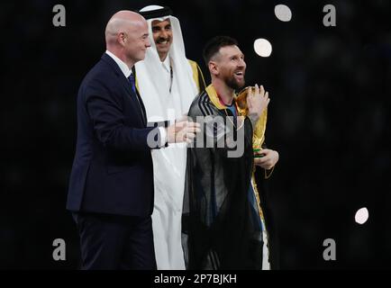 Il Lionel messi argentino abbraccia il Trofeo della Coppa del mondo come Emir of Qatar, Sheikh Tamim bin Hamad al Thani e il presidente della FIFA Gianni Infantino guardano in rassegna durante la finale della Coppa del mondo FIFA allo stadio di Lusail, in Qatar. Data immagine: Domenica 18 dicembre 2022. Foto Stock