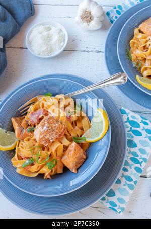 Salmone con pasta e salsa di pomodoro sui piatti Foto Stock