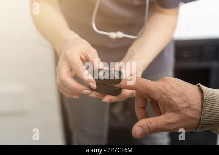 Misurazione del livello di ossigeno e della frequenza del polso con un pulsossimetro portatile - un uomo monitora la sua salute Foto Stock