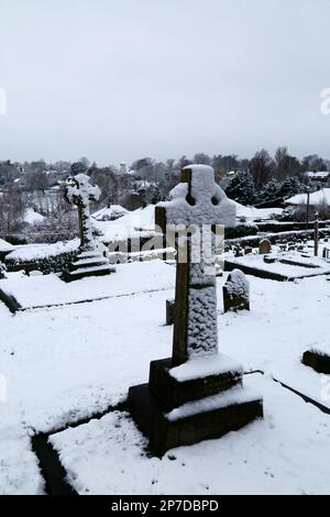 Marzo 8th, 2023. Bidborough, Kent. Lapidi nel sagrato di San Lorenzo dopo una fresca nevicata notturna. In lontananza sullo skyline si trova l'ex mulino a vento di Bidborough, ora trasformato in una casa. Foto Stock