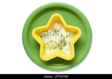 uova di quaglia strapazzate. le uova in una muffa di silicone gialla giacciono su una piastra di ceramica verde. insalata di crescione su un piatto Foto Stock