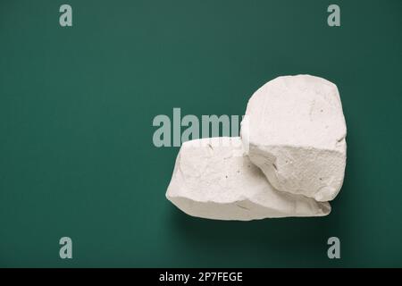 i pezzi naturali di pietre minerali del gesso sono sullo sfondo verde della lavagna, vista dall'alto, spazio della copia Foto Stock