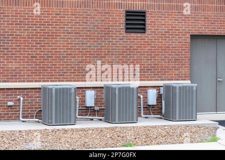 Vista orizzontale dei compressori dell'aria condizionata collegati all'esterno di un edificio commerciale. Foto Stock