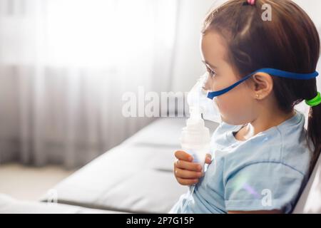 Bambina in una maschera, trattamenti del tratto respiratorio con un nebulizzatore a casa Foto Stock