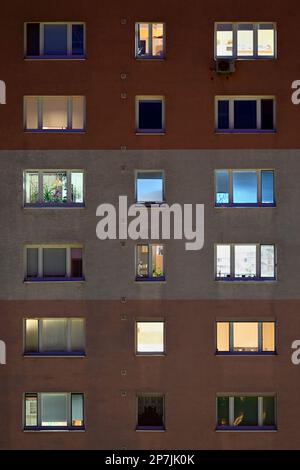 Finestre degli appartamenti illuminate di notte in un edificio urbano in formato verticale Foto Stock