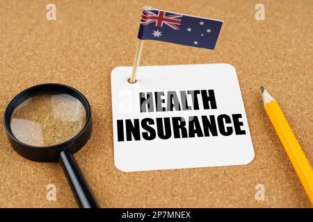 Sulla tabella è la bandiera dell'Australia, una matita, una lente d'ingrandimento e un foglio di carta con l'iscrizione - assicurazione sanitaria Foto Stock