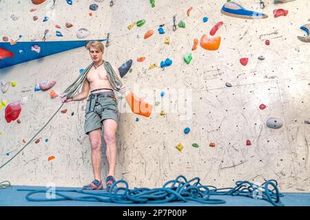 avvolgimento di una corda da arrampicata da parte di un giovane arrampicatore Foto Stock