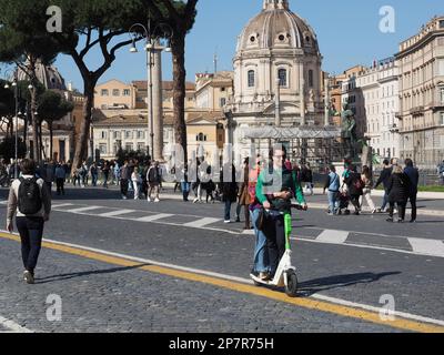 Giovane coppia che utilizza uno scooter elettrico a noleggio in Via dei fori Imperiali a Roma Foto Stock