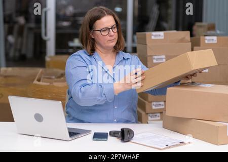 Laptop PMI giovane imprenditore per gestire le operazioni di imballaggio degli ordini di vendita on-line scatole. e-commerce Foto Stock