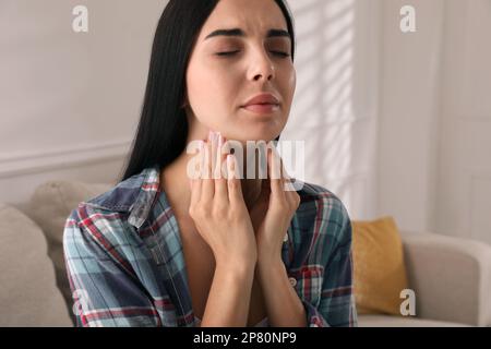 Giovane donna che fa l'esame di auto della tiroide nel paese Foto Stock