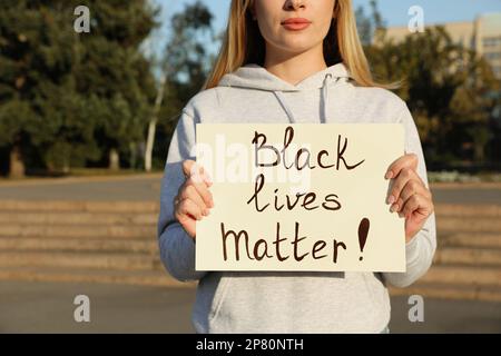 Giovane donna che tiene segno con la frase Black Lives Matter Outdoor, primo piano. Concetto di razzismo Foto Stock