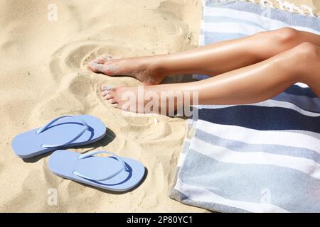 Donna che riposa e pantofole sulla spiaggia di sabbia, primo piano Foto Stock