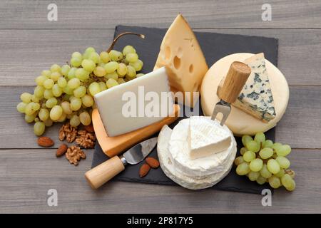 Diversi tipi di deliziosi formaggi e snack sul tavolo di legno, vista dall'alto Foto Stock