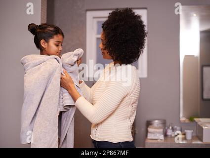 Ti lascia asciugare. una madre che asciuga la figlia con un asciugamano in bagno. Foto Stock
