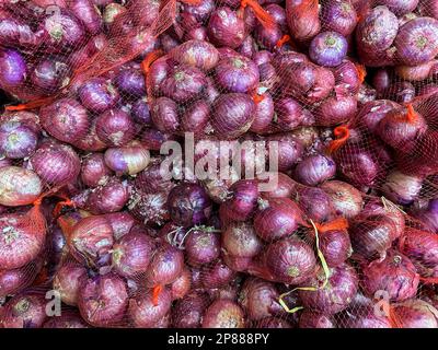 Piccoli sacchetti di cipolla indiana o cipolla indiana rossa per la vendita ad un mercato fresco dell'alimento in India. Vista dall'alto di cipolle rosse o cipolle viola Foto Stock