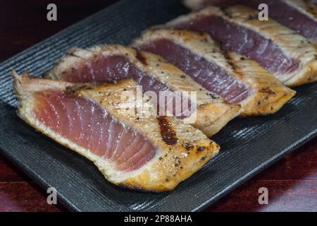 Stile giapponese di temaki con filetto di pesce sgombro su piatto nero, cibo asiatico, cibo tradizionale giapponese, primo piano. Foto Stock