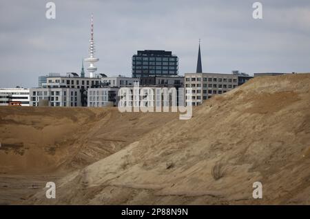 Amburgo, Germania. 08th Mar, 2023. La silhouette di HafenCity con appartamenti a Baakenhafen è vista dietro il riporto di sabbia in preparazione per il cantiere di Grasbrook nel porto. Alla conferenza stampa annuale di HafenCity Hamburg GmbH sono state presentate, insieme ad altri argomenti, le strategie future nelle aree di sviluppo urbano di Grasbrook, Science City Hamburg Bahrenfeld, Billebogen e HafenCity. Credit: Christian Charisius/dpa/Alamy Live News Foto Stock