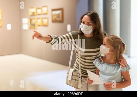 Ragazza con madre in maschere guardando con interesse agli oggetti d'arte Foto Stock