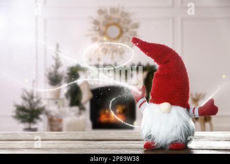 Divertente gnome di Natale su tavolo di legno in camera con decorazioni festive. Spazio per il testo Foto Stock