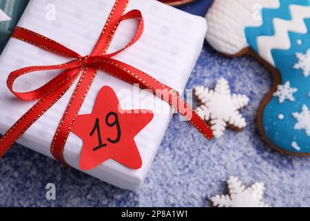 Confezione regalo con etichetta di carta e biscotti di pan di zenzero su sfondo blu, primo piano. 19 dicembre - San Nicola Foto Stock