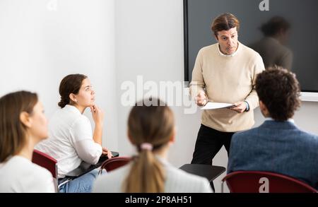 Professore esperto che spiega il soggetto ad aula piena di studenti Foto Stock