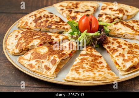 Mexican quesadilla con pollo, formaggio e peperoni sul tavolo di legno Foto Stock