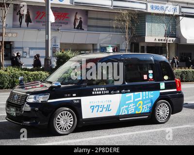 TOKYO, GIAPPONE - 26 febbraio 2023: Taxi in una strada a Ginza. Un cinema Toei è sullo sfondo. L'auto è una Toyota JPN taxi. Foto Stock