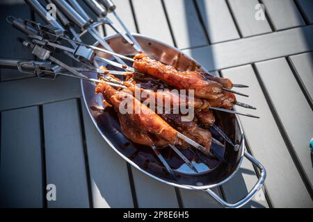 Grigliare gli spiedini con pollo marinato in un recipiente di metallo. Foto Stock