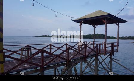 Ponte sul mare da tavole di legno con gazebo sopra l'acqua di mare sulla spiaggia Foto Stock