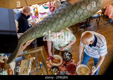 Vista dall'alto verso il basso dell'interno della nave da frittella con decorazioni in primo piano e la gente passava il buffet corrente ottenendo cibo. Foto Stock