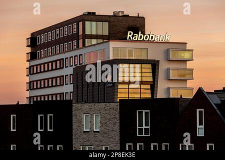 I contadini olandesi banca Rabobank sorge sopra le case residenziali a cielo arancione alba. Foto Stock