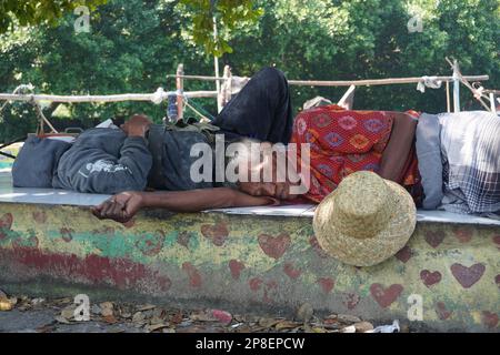 vecchio pescatore in un cappello che dorme vicino alla loro barca Foto Stock