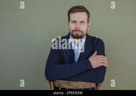 Ritratto di un bell'uomo seduto davanti su una sedia Foto Stock