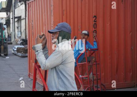 primo piano il lavoratore portuale si riposa dal cumulo di merci alla nave Foto Stock